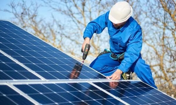 Professional solar installer from Voltmen Solar performing maintenance on a rooftop system